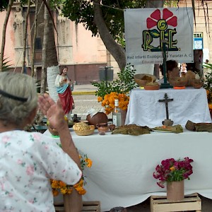 Una vieja (old woman) crosses herself while gazing at a Hanal Pixán altar in the Plaza Grande in Merida. <a href=></a>